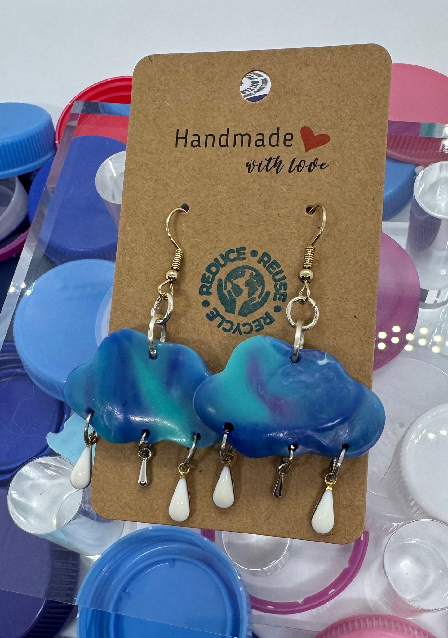 Earrings on a card with colorful bottle caps in the background