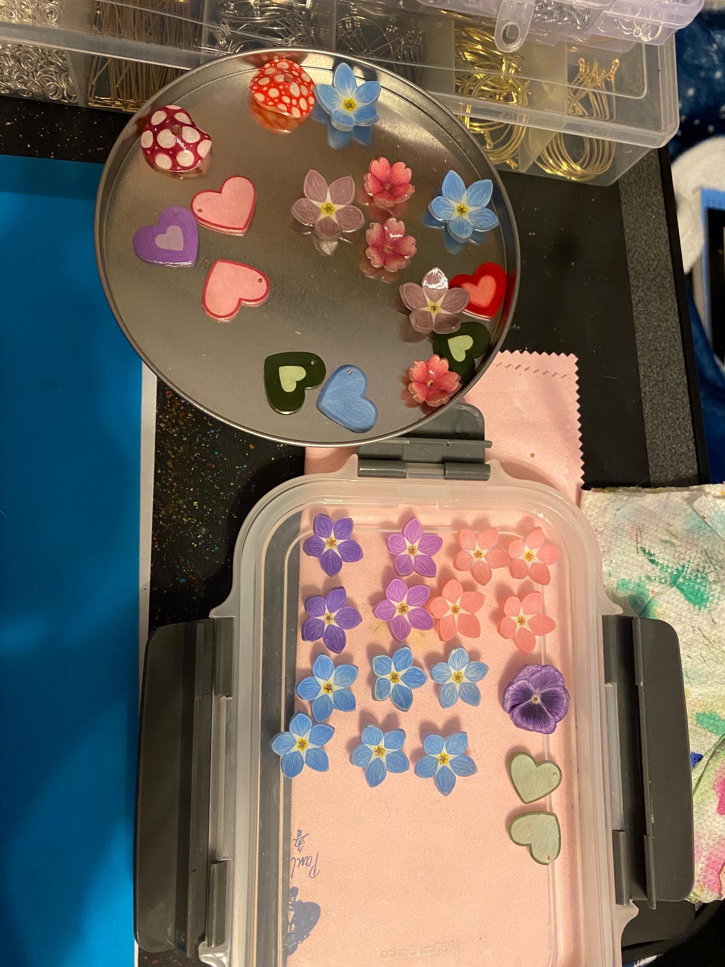 Small open container with decorative stickers of flowers and hearts on a reflective surface.