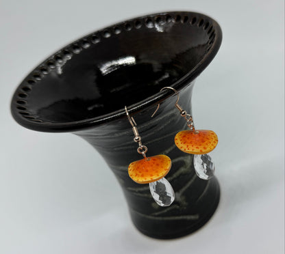 Black bell-shaped object with orange and silver decorative elements on a white background
