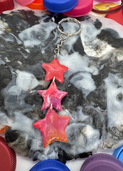 Decorative star-shaped earrings on a textured surface with colorful bottle caps around.