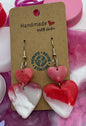 Heart-shaped earrings on brown cards with a pink and white background