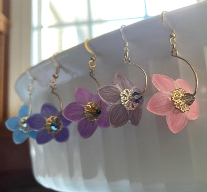Floral earrings on a white surface with a blurred background
