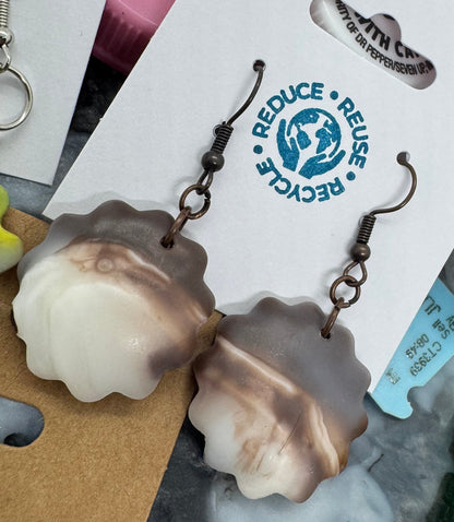 Collection of earrings and a card with recycling symbols on a white background