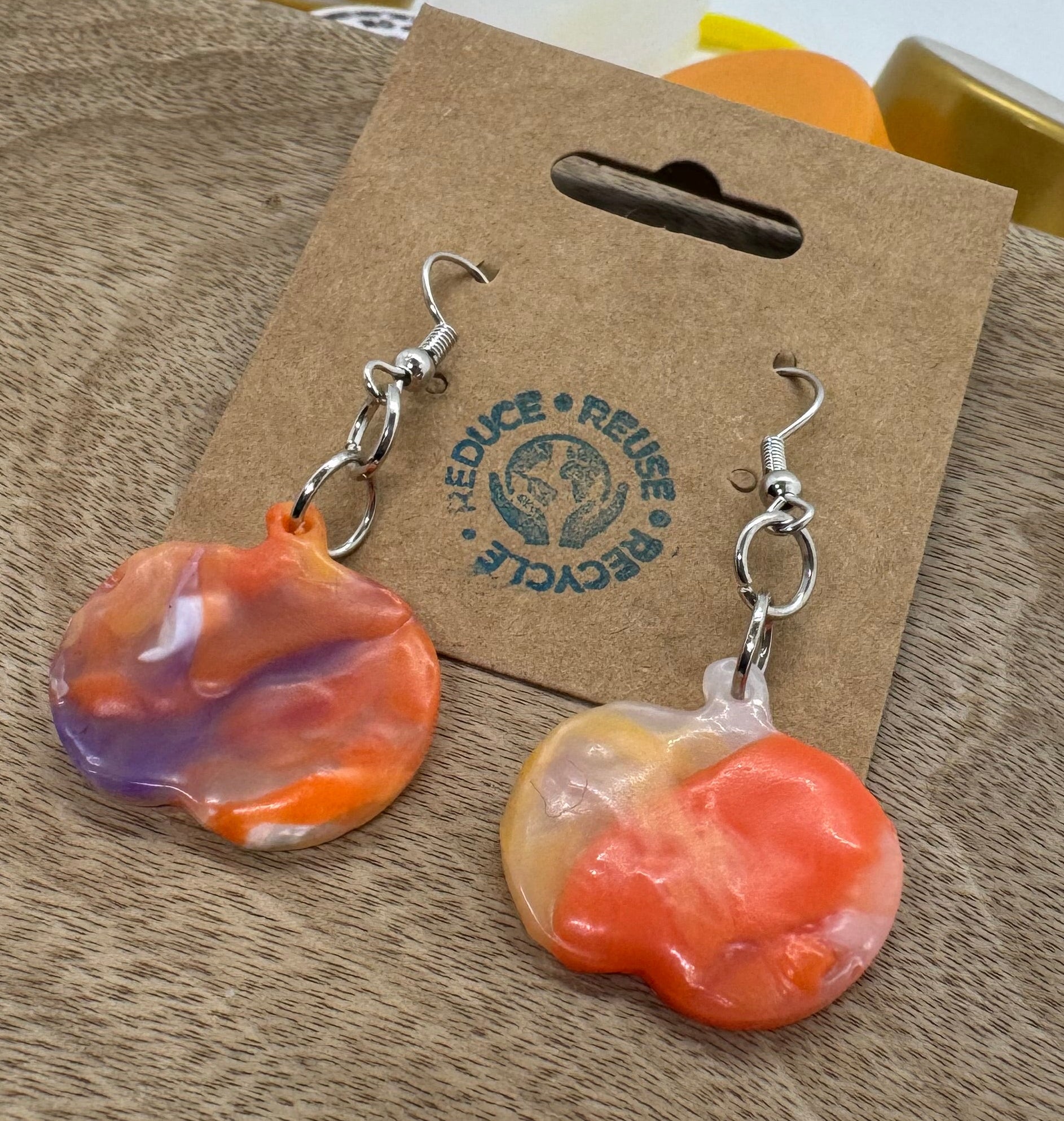 Colorful earrings on a cardboard backing with a visible brand logo.