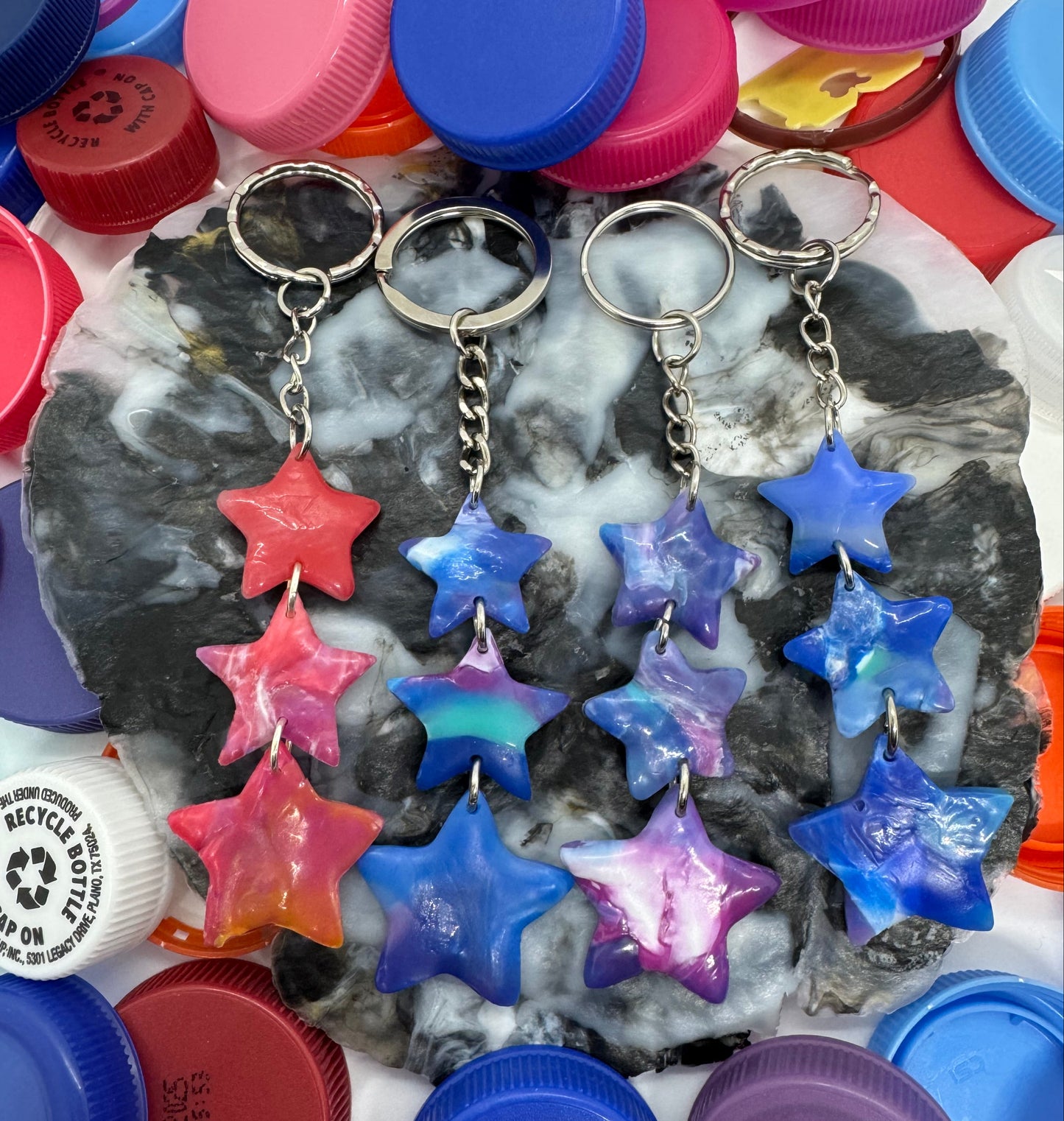 Colorful star-shaped keychains and bottle caps on a textured surface