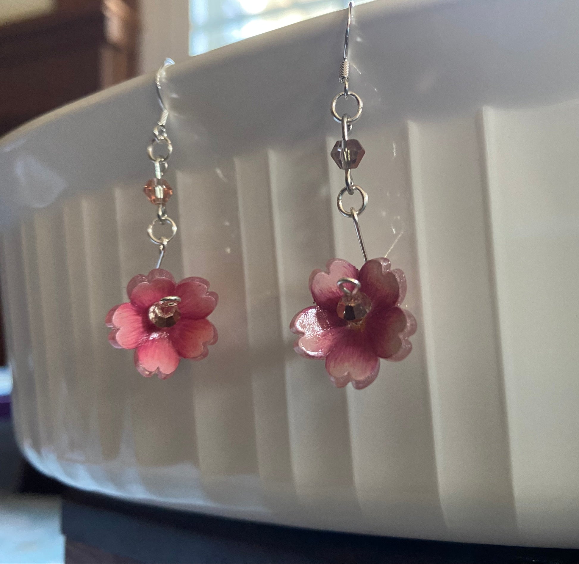 Pink flower-shaped earrings on a white dish