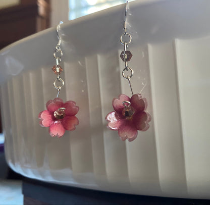 Pink flower-shaped earrings on a white dish