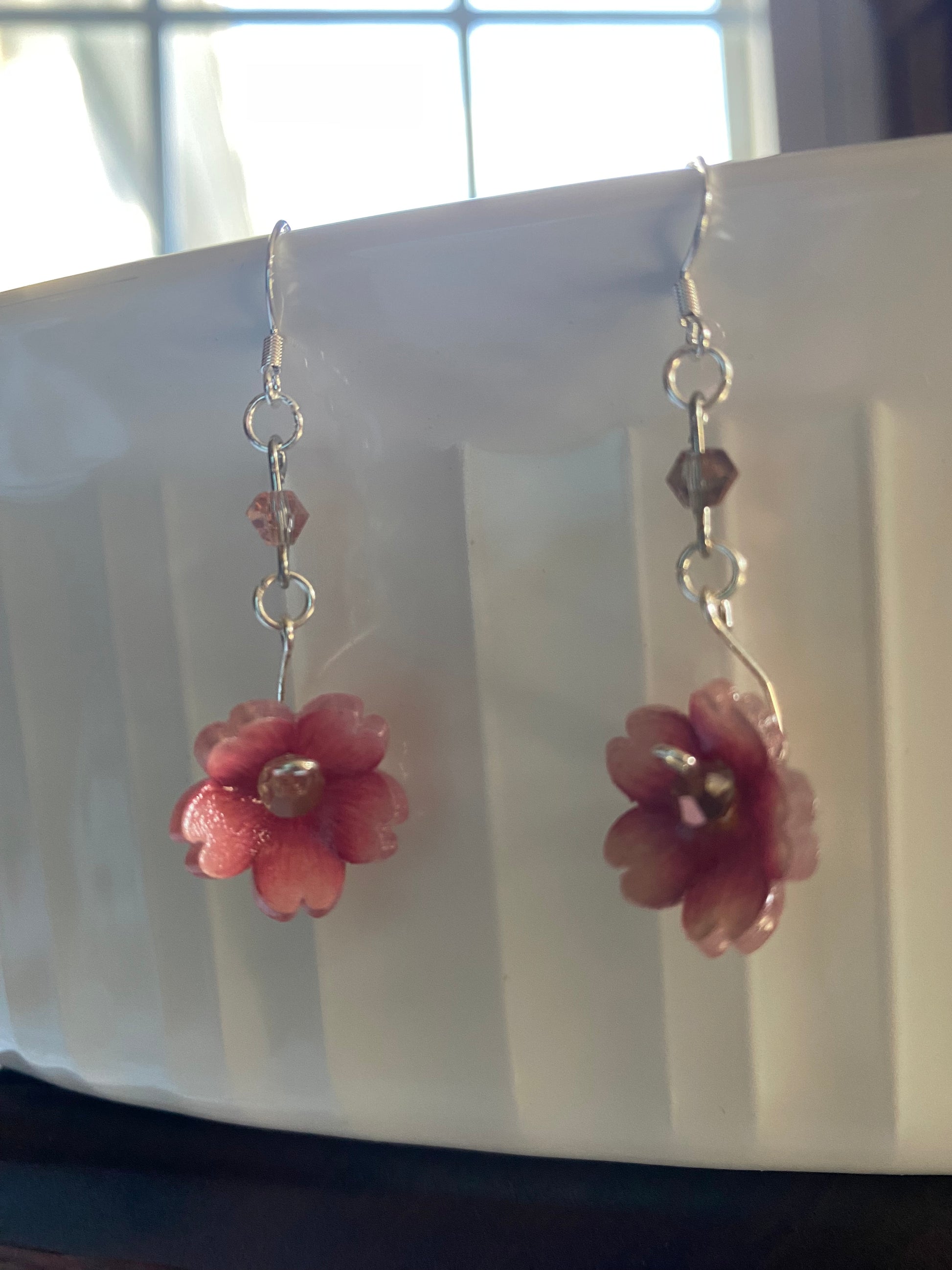 Silver bracelet with pink flower-shaped charms on a white background