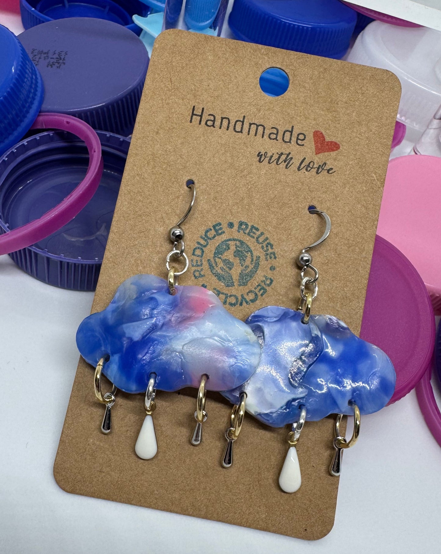 Handmade jewelry on a card with colorful bottle caps in the background