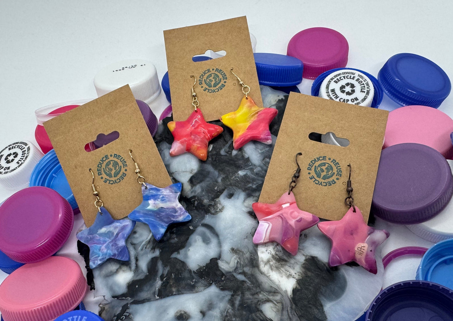 Colorful bottle caps with earrings on display cards on a white background