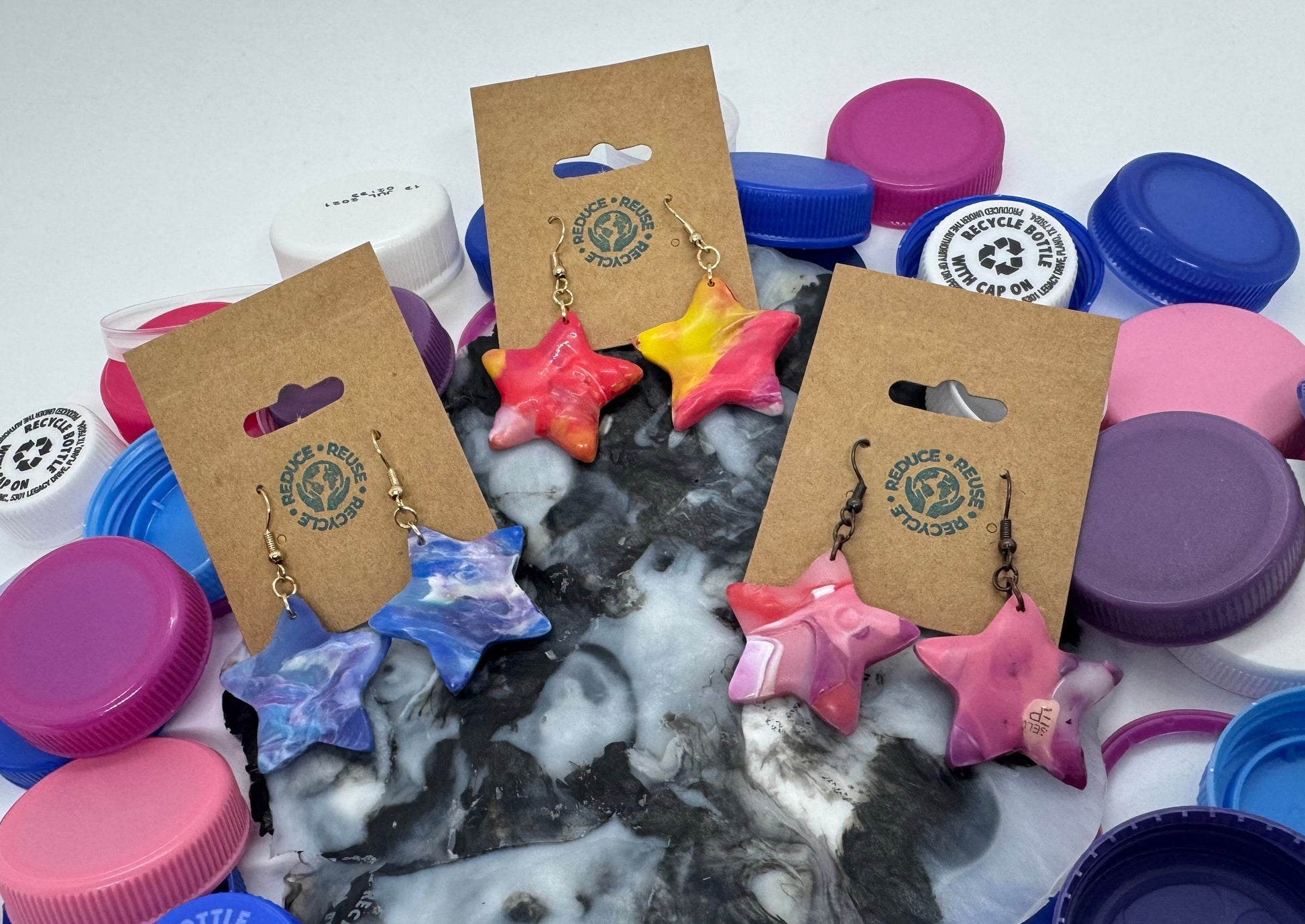 Colorful bottle caps with earrings on display cards on a white background