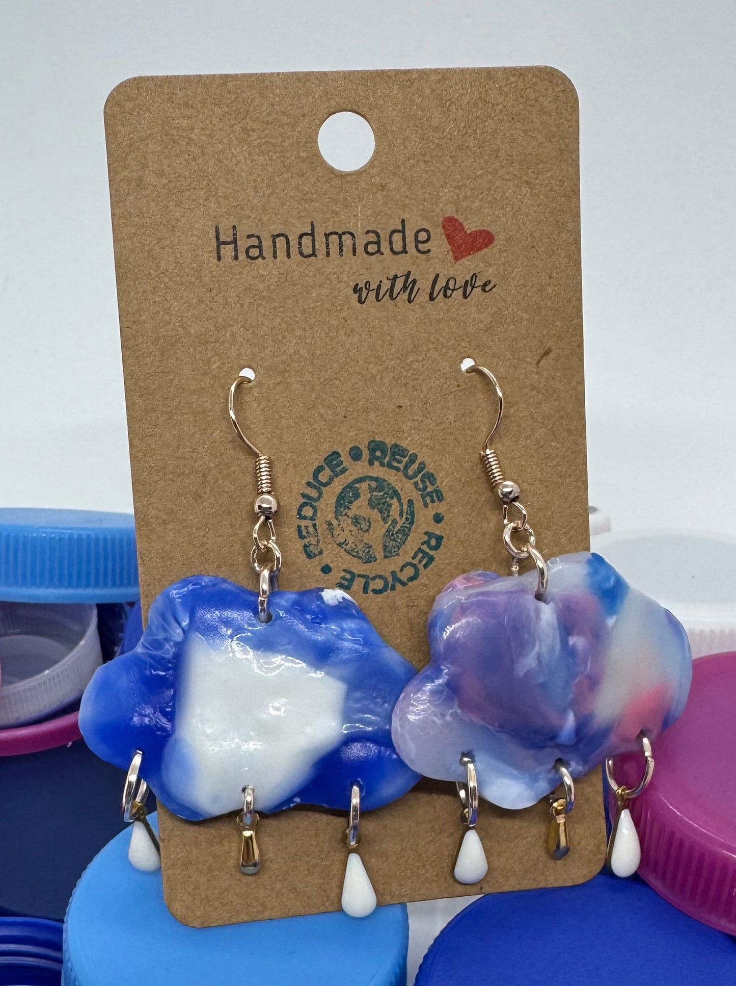 Pair of earrings on a card with colorful bottle caps in the background