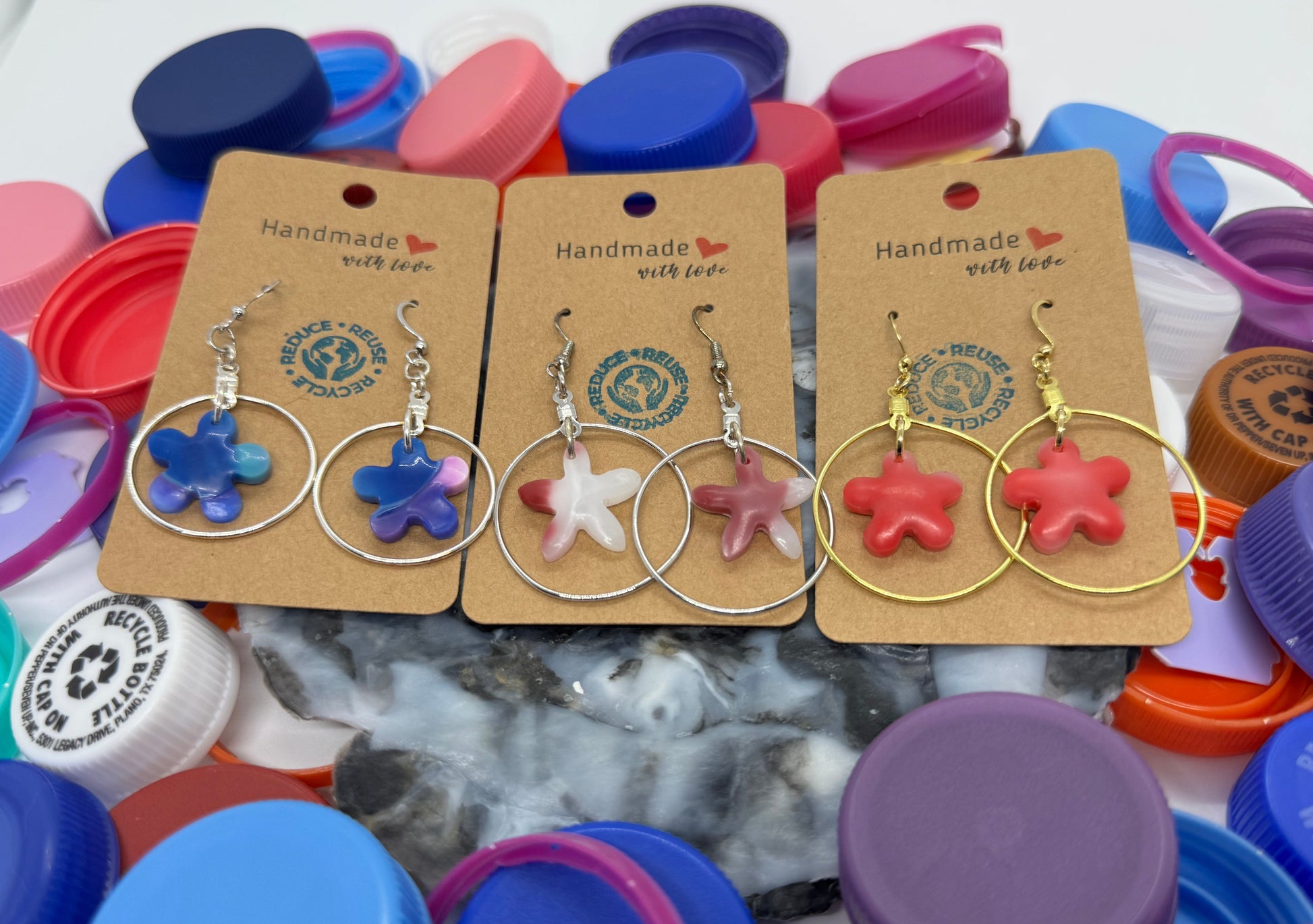 Star-shaped earrings on cards with colorful bottle caps in the background