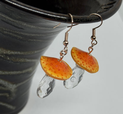 Earrings with orange and clear glass stones on a dark background