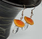 Earrings with orange and clear glass stones on a dark background