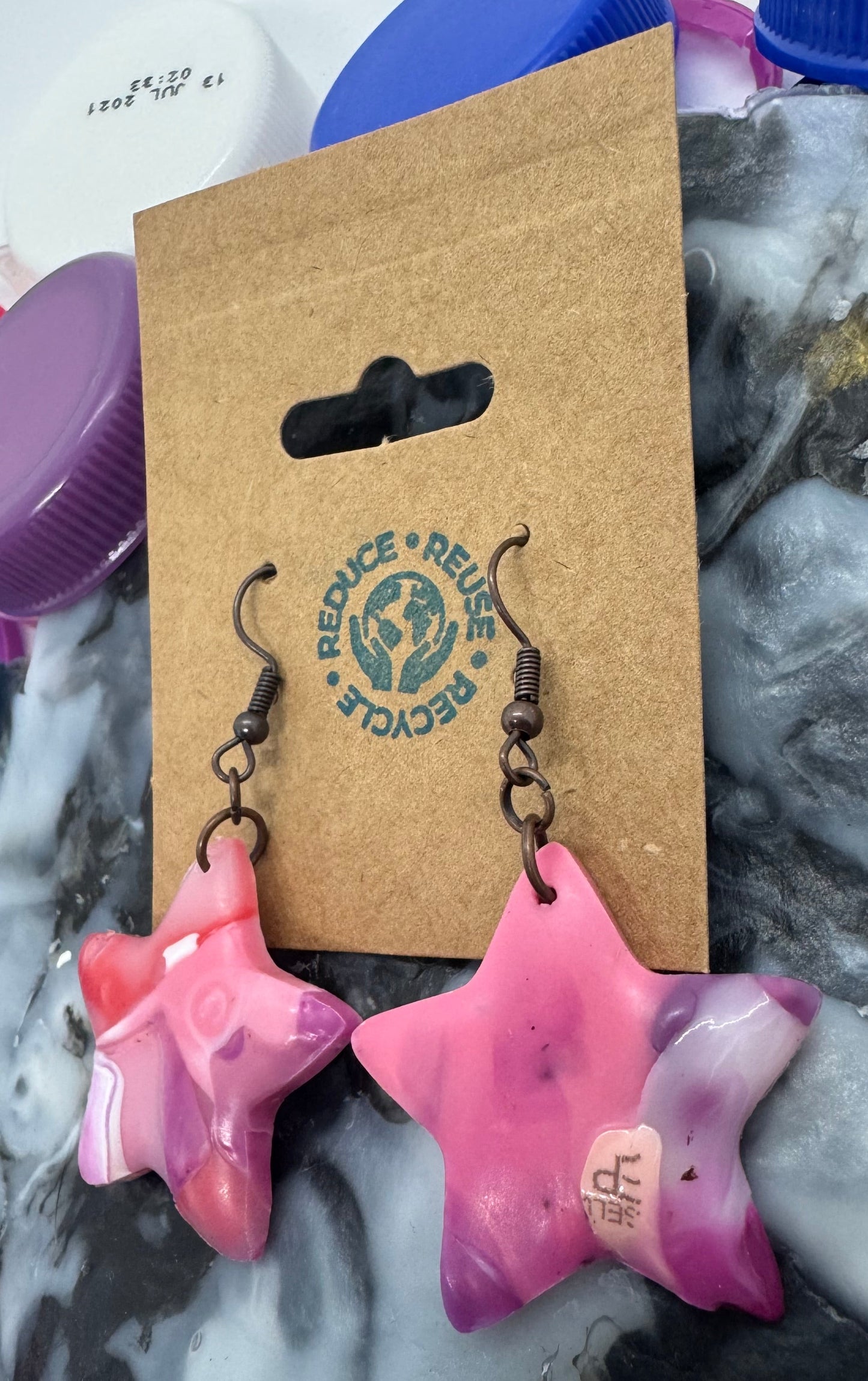 Pink and purple plastic items on a textured surface with a cardboard box featuring branding.