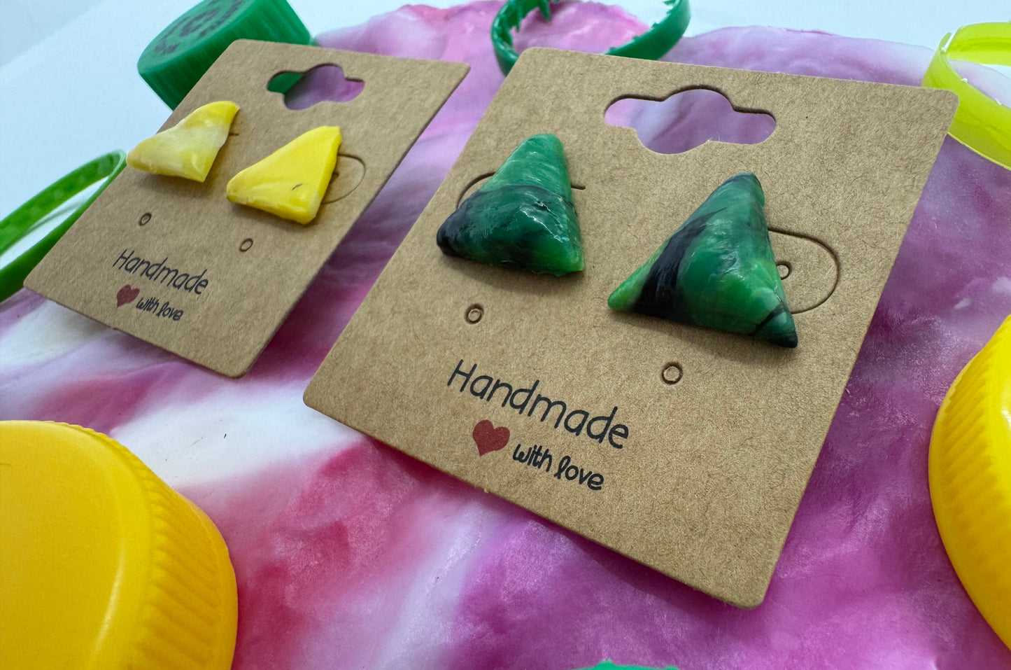Green triangle earrings on a brown card with 'Handmade with Love' text, against a colorful background.