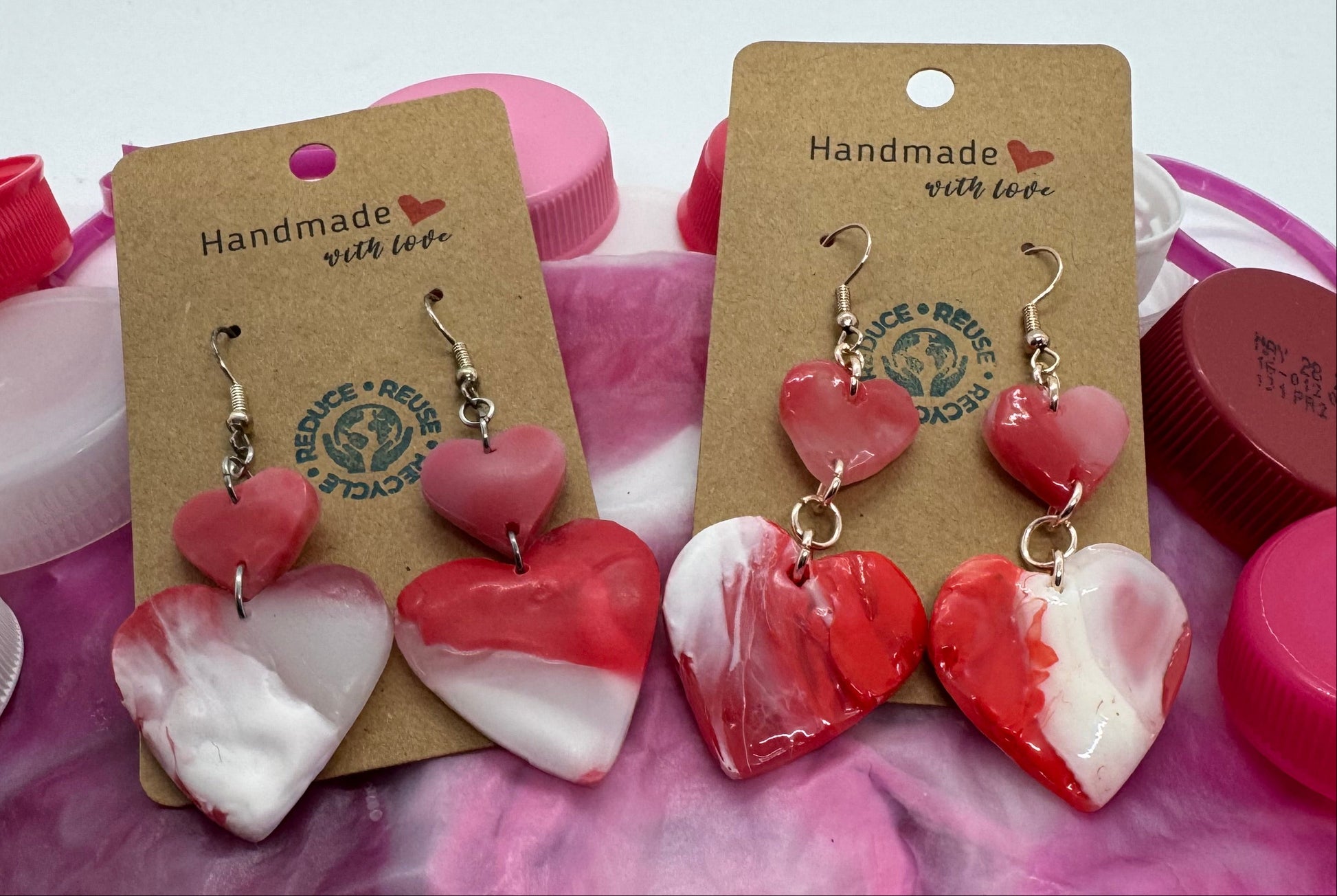 Heart-shaped earrings on display with a pink and white marbled background