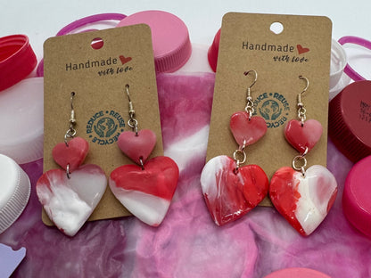 Pair of earrings on display with colorful bottle caps in the background