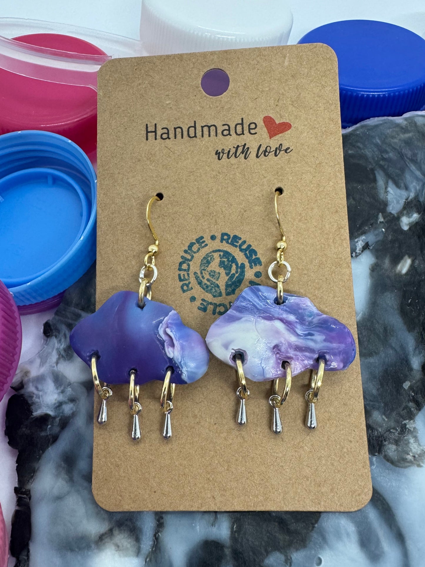 Pair of purple earrings on a 'Handmade with Love' card against a marble background.
