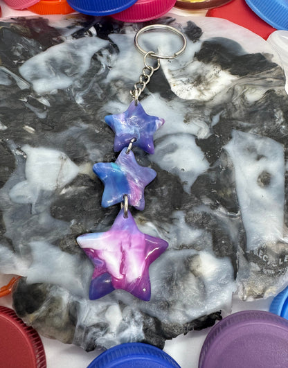 Decorative stone with star-shaped decorations and a keychain, surrounded by colorful bottle caps.