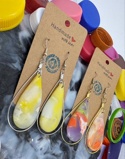 Colorful earrings on display with 'Handmade with Love' cards against a textured background.