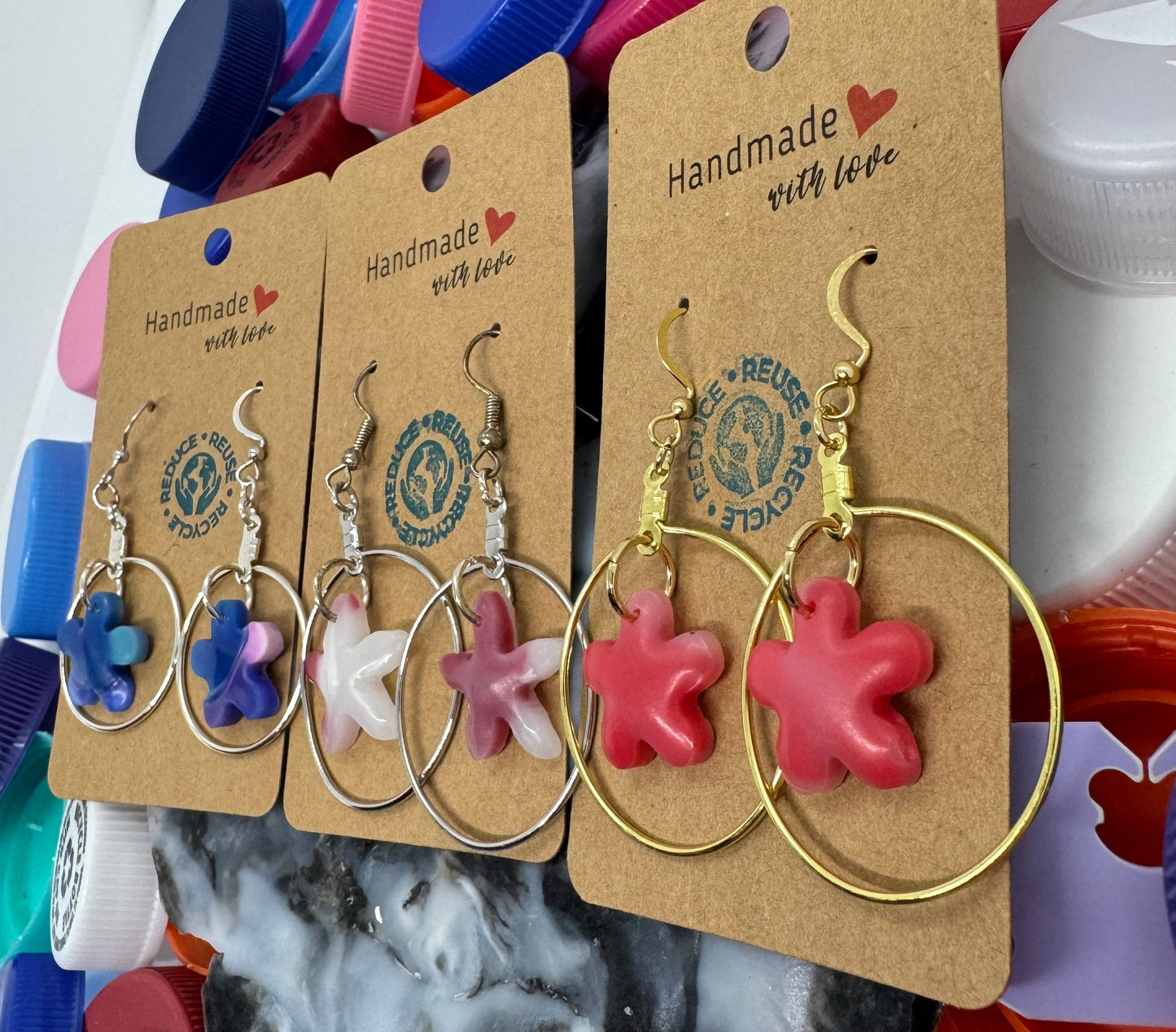Set of earrings on display with colorful bottle caps in the background