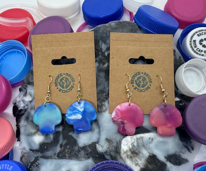 Earring cards with blue and pink earrings surrounded by colorful bottle caps.