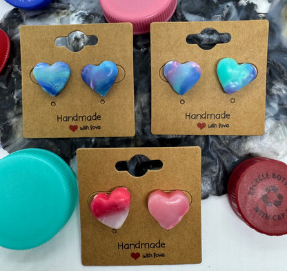 Heart-shaped earrings on cardboard cards with bottle caps in the background