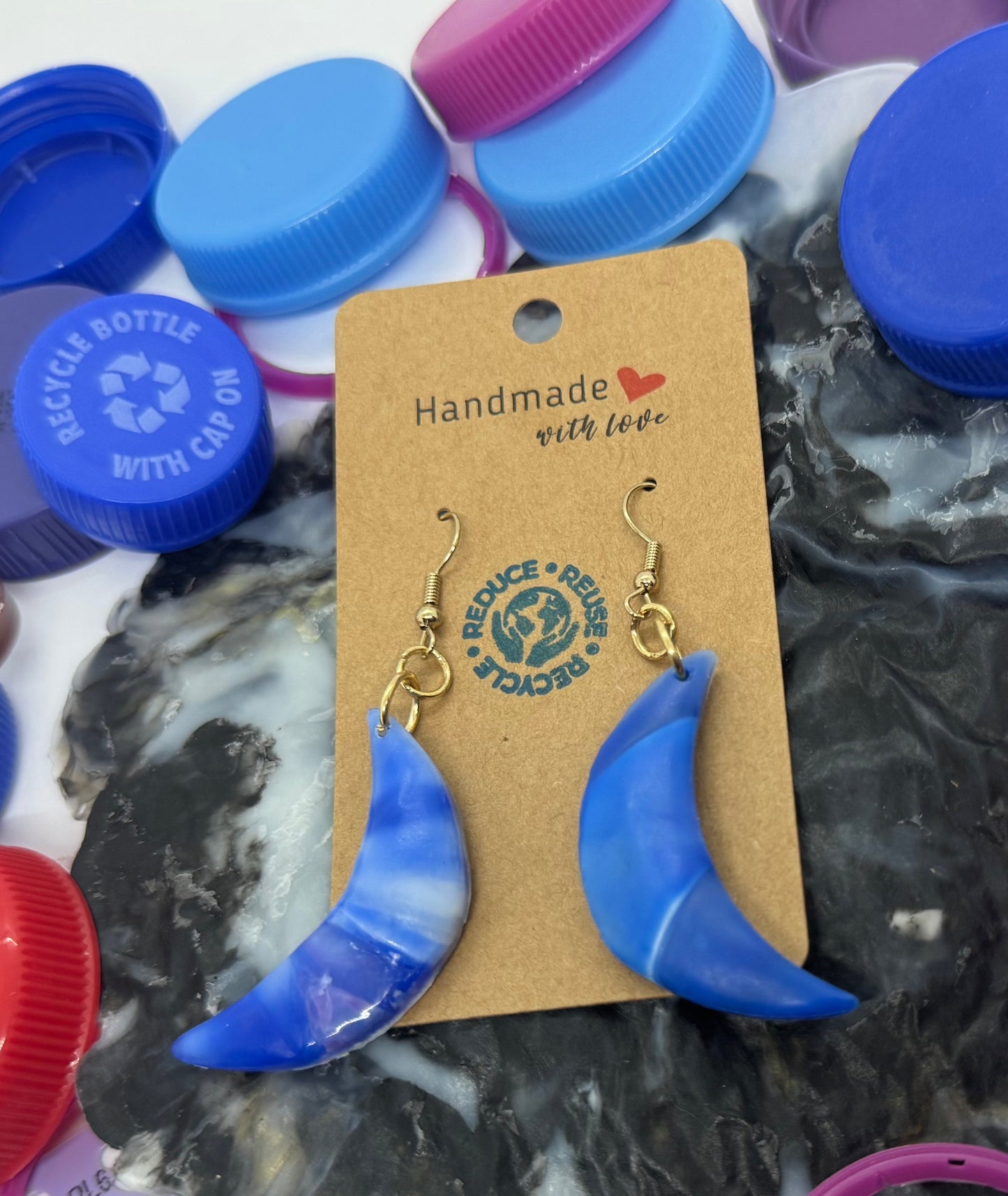 Colorful bottle caps with a pair of blue earrings on a white background