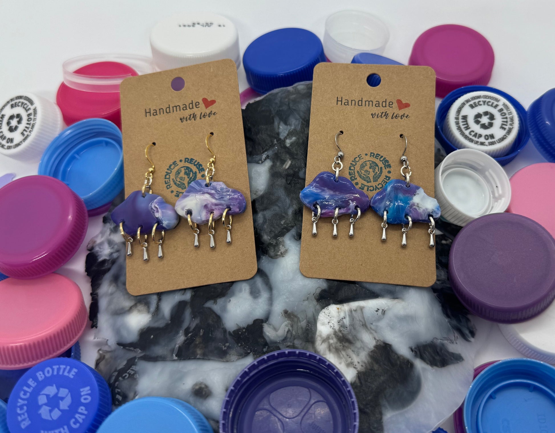 Handmade earrings on display with colorful bottle caps on a marble surface