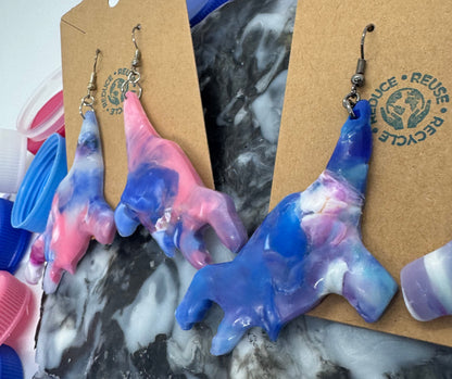 Colorful plastic items on a marble surface with 'Recycle' sign in the background