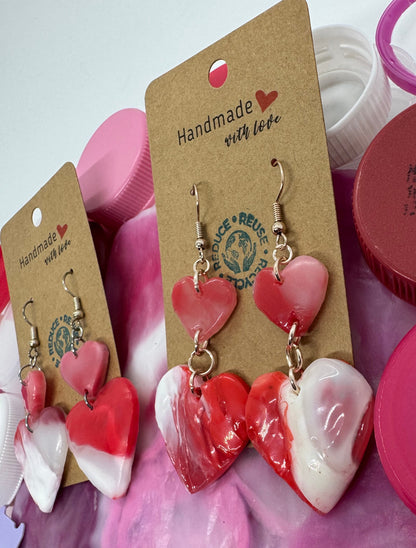 Heart-shaped earrings on a card with 'Handmade with Love' tag, surrounded by pink containers.
