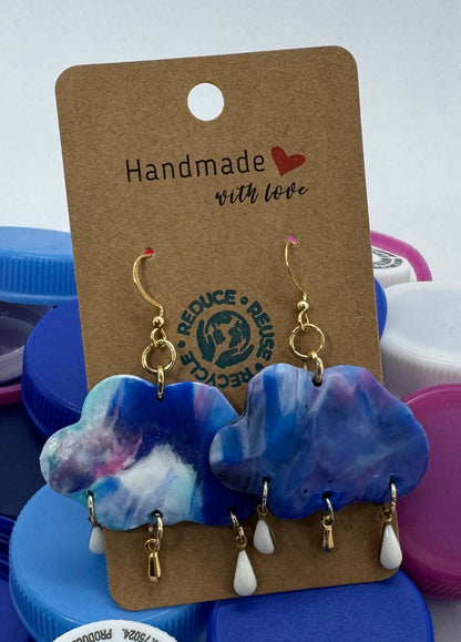 Blue floral earrings on a card with colorful bottle caps in the background