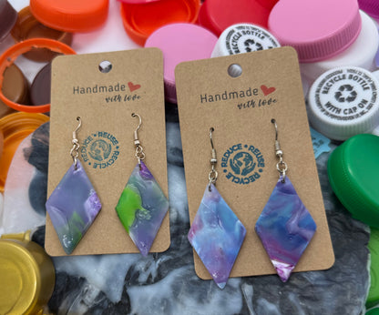 Handmade earrings on cards with colorful bottle caps in the background