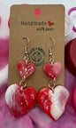 Heart-shaped earrings on a Starbucks branded card with pink lids in the background