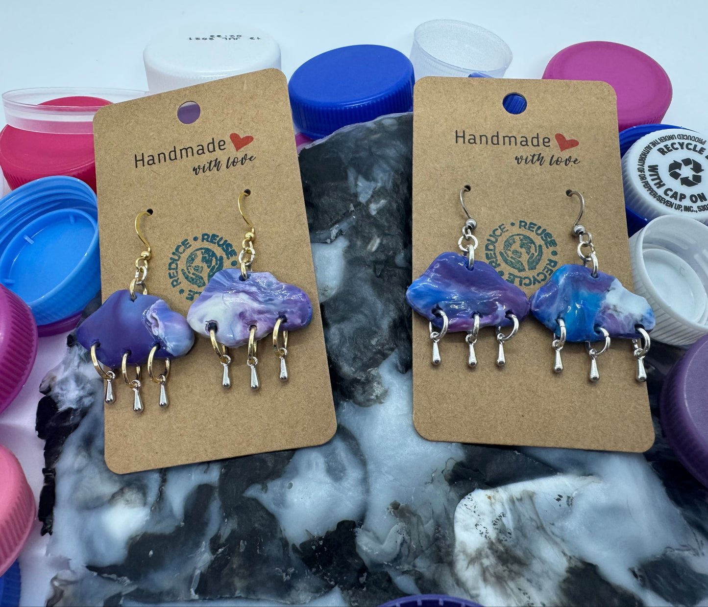 Handmade earrings on display with a variety of colorful bottle caps in the background.