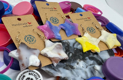 Colorful plastic bottle caps with handmade jewelry on a white surface