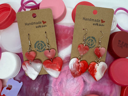 Heart-shaped earrings on display with colorful bottle caps in the background
