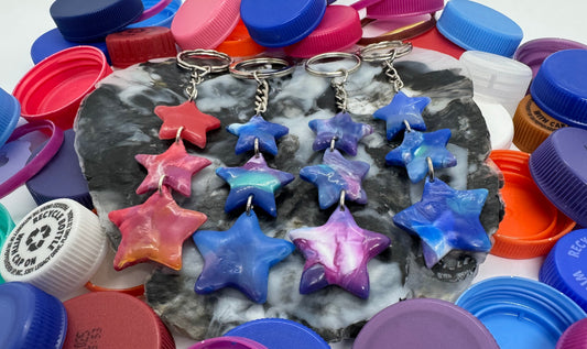 Colorful bottle caps with star-shaped objects and keychains on a textured surface.