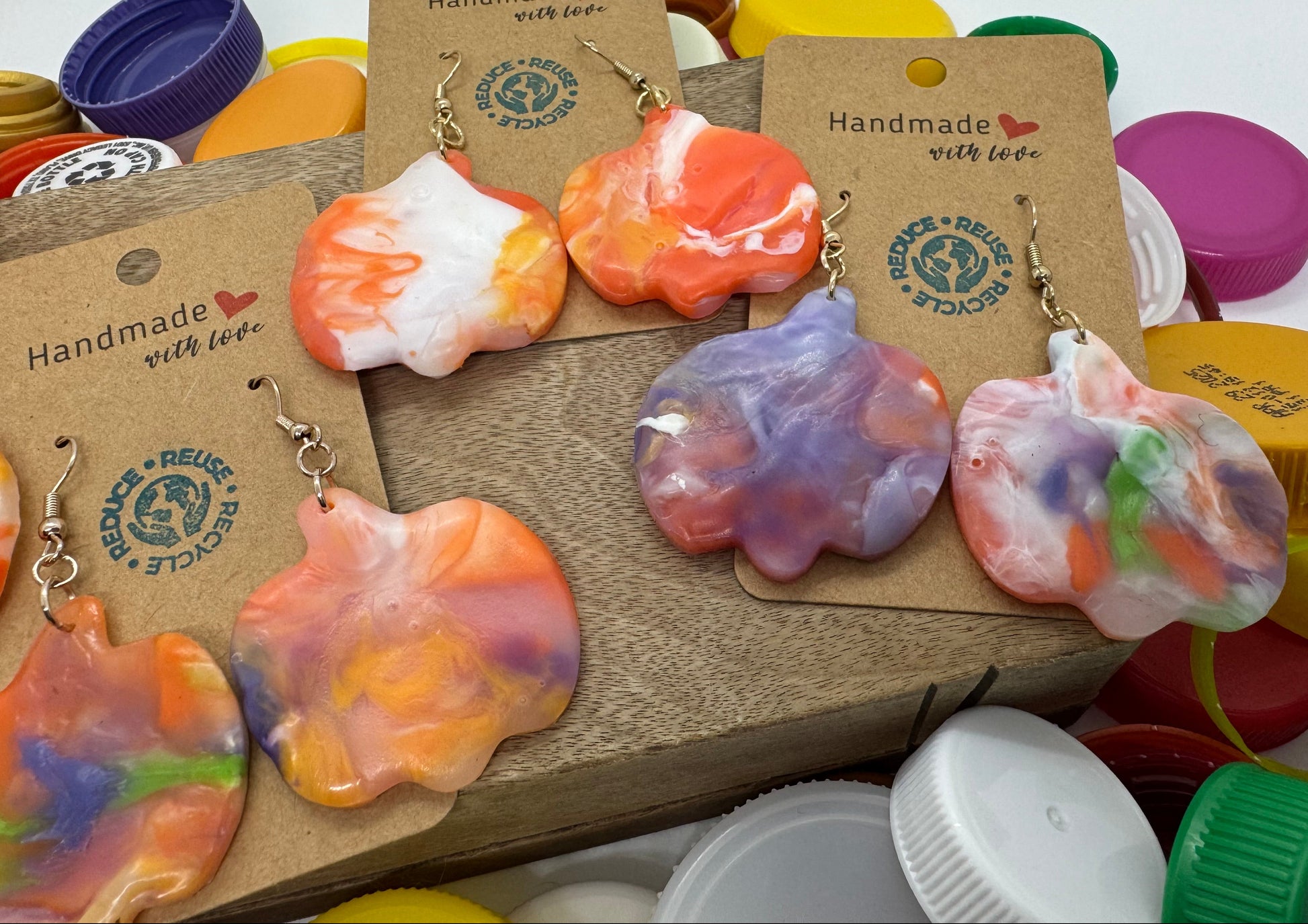 Colorful earrings on display with branded cards against a white background