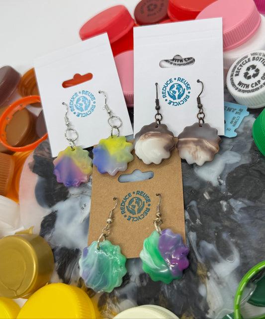 Colorful earrings on display with a variety of plastic bottle caps in the background.