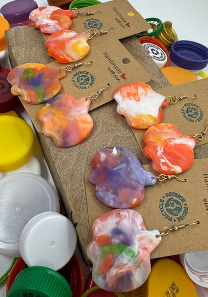 Colorful tie-dye earrings on display with branded cards against a colorful background.