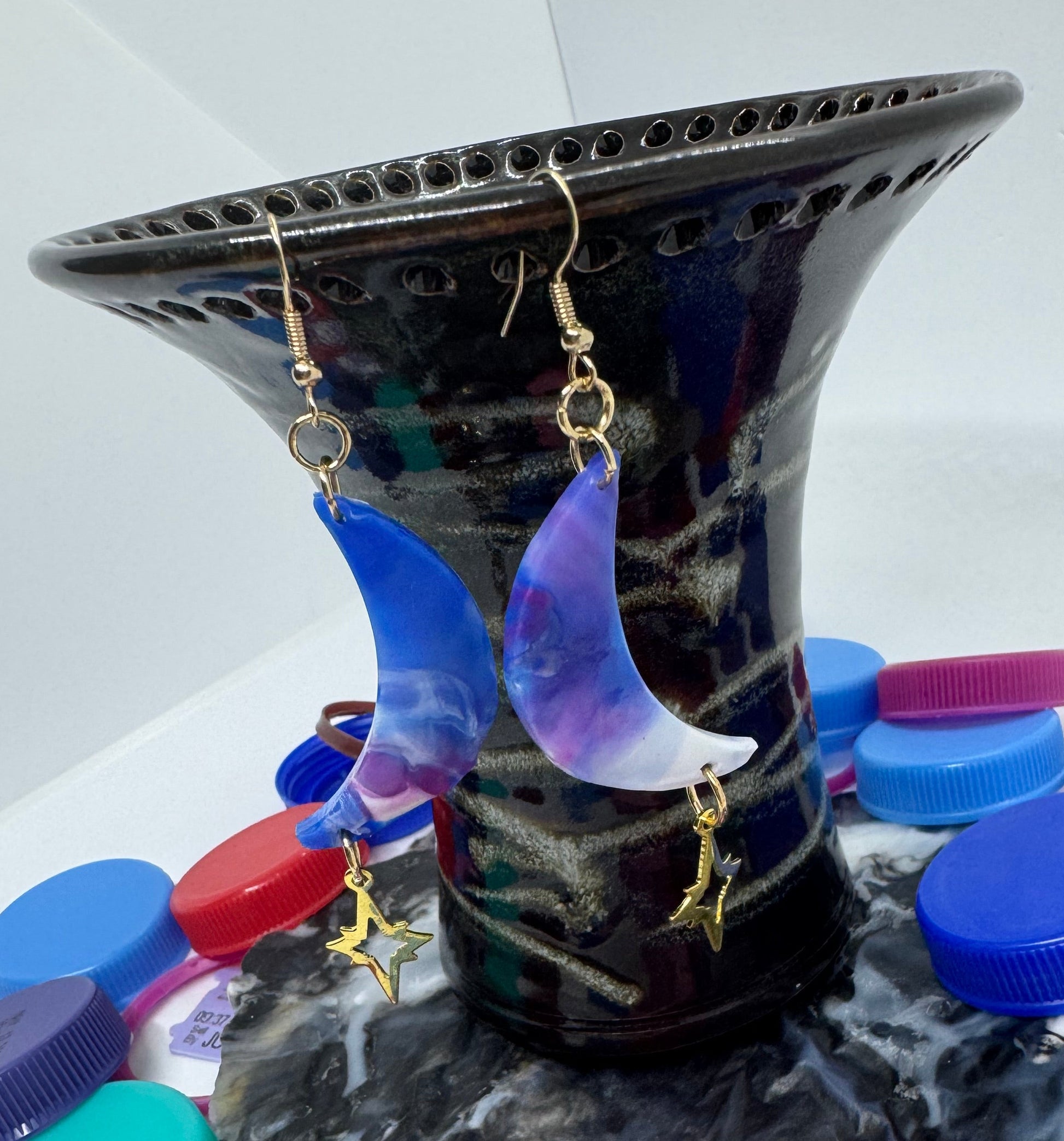 Colorful bottle caps on a white surface with a black container.