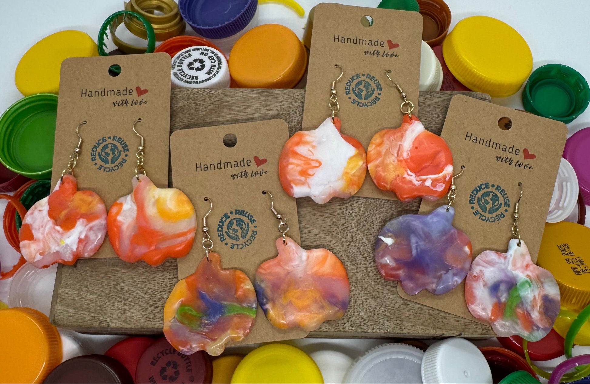 Colorful resin jewelry on display with various bottle caps in the background