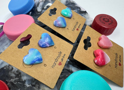 Heart-shaped earrings on brown cards with 'Handmade' text, surrounded by colorful bottle caps.