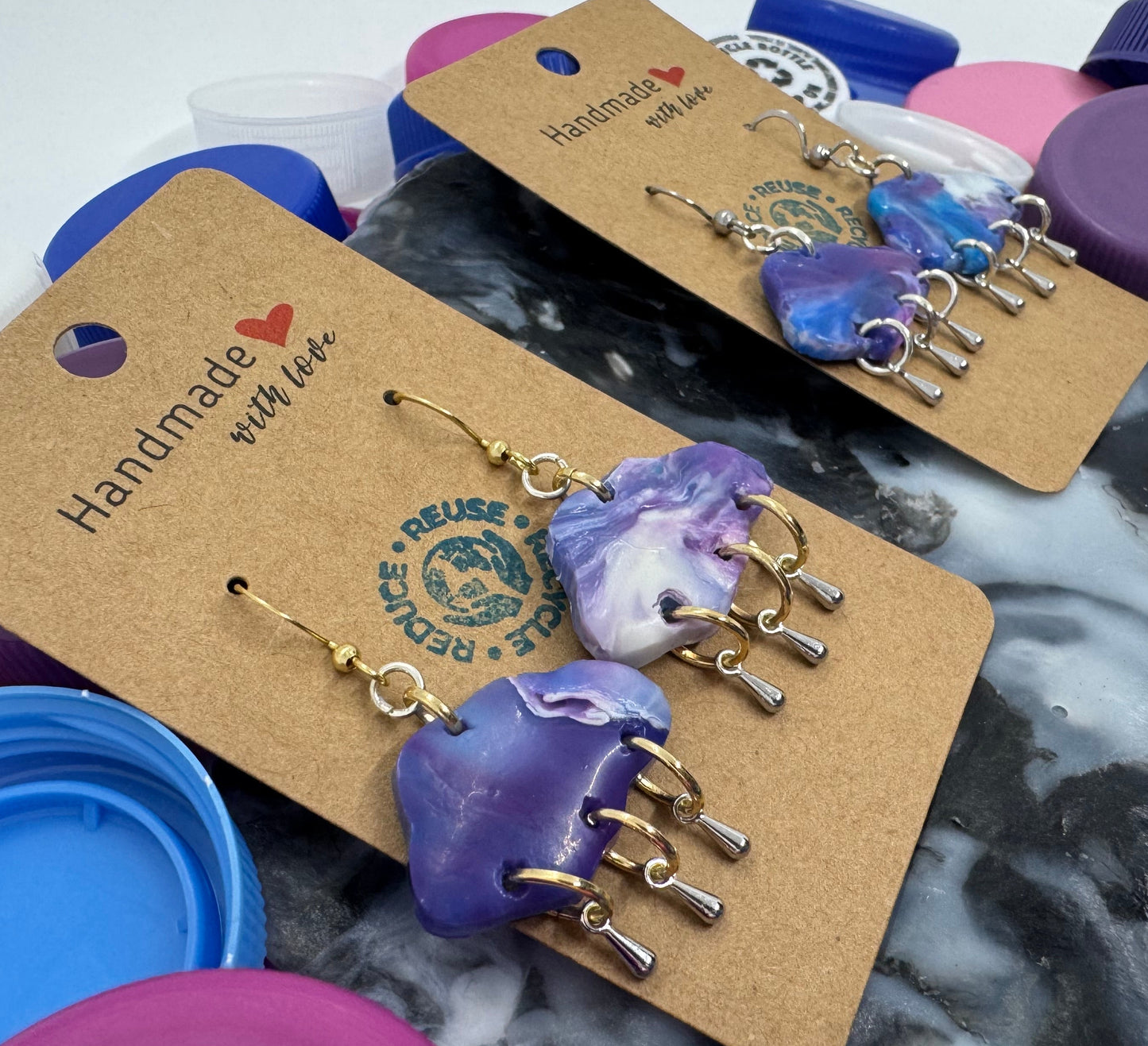 Handmade earrings on a cardboard backing with 'Handmade with Love' text, displayed on a marble surface.
