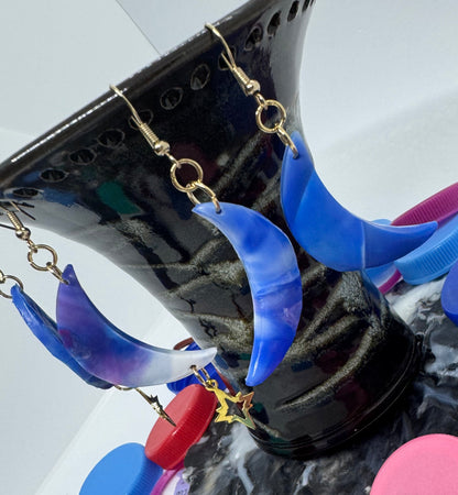 Blue and purple earrings on a black stand with a white background
