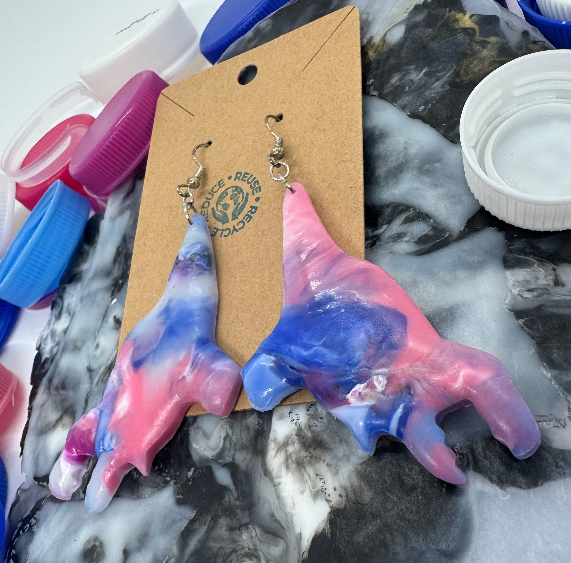 Colorful hand-shaped soap with a card and pendant on a textured surface