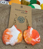 Handmade earrings on a wooden stand with colorful bottle caps in the background